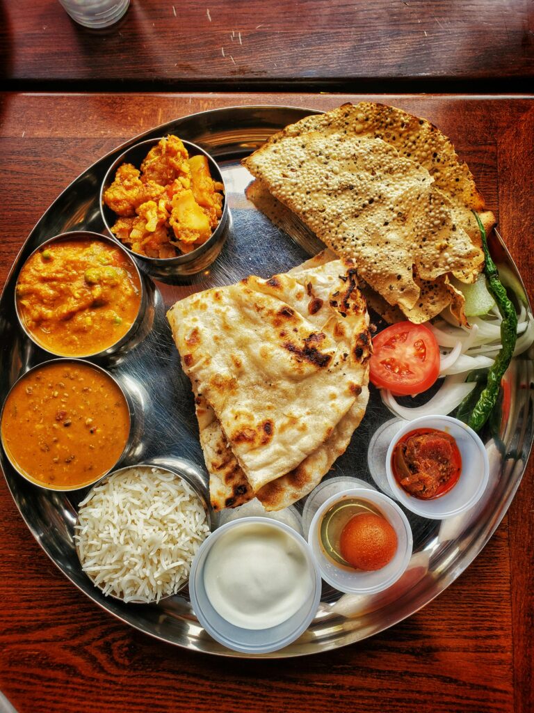 A proper homemade food plate filled with vegetable dish , flatbread, rice and dessert.